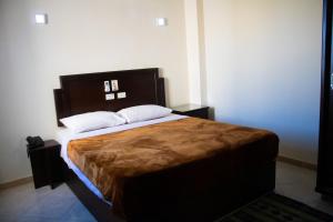 沙姆沙伊赫Sharks Bay Oasis Resort & Butterfly Diving Center的一间卧室配有一张大床和木制床头板