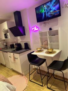 圣布里厄Honey Room22的厨房配有桌子和两把椅子以及电视。