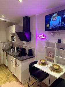 圣布里厄Honey Room22的厨房配有桌子,墙上配有电视。