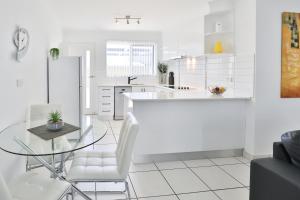 米尔迪拉112号橄榄公寓的白色的厨房配有玻璃桌和白色椅子