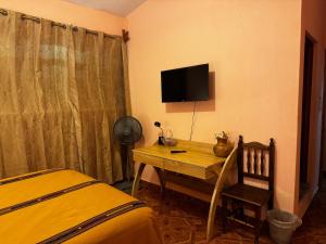 帕纳哈切尔Casa Esperanza的一间卧室配有一张桌子、一台电视和一张床