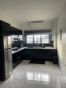 帕拉马里博Luxe appartementen Paramaribo Noord的厨房配有黑色橱柜和不锈钢冰箱