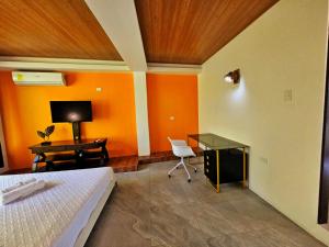 弗洛勒斯Las Luciernagas Hotel Boutique的一间卧室设有橙色的墙壁、一张桌子和一张床
