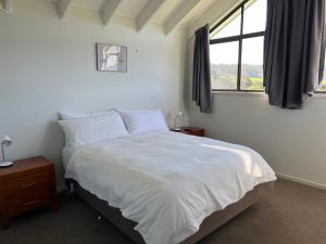 纳鲁马Black Bream Point Cabins的卧室配有白色的床和窗户。