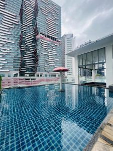 吉隆坡Reizz Residence By D'Amour的一座带红色遮阳伞和高楼建筑的游泳池