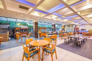 万隆万隆达戈1O1酒店的餐厅设有木桌、椅子和窗户。