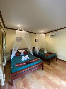 考索Khao Sok River & Jungle Bungalow的一间卧室配有两张带蚊帐的床