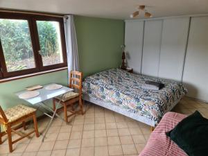 BréelChambre à la ferme, les vergers du Muscardin的一间卧室配有一张床、一张桌子和一个窗户。