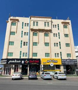 锡卜ALJAWHARA INN HOTEL的一座大型建筑,前面有汽车停放