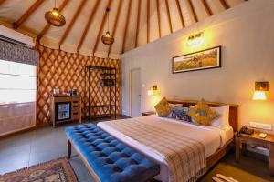 SrimangalaMachaan Wilderness Lodge Nagarahole的一间卧室配有一张大床和蓝色长凳