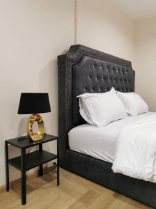 芭堤雅市中心The One Hotel的一张带黑色床头板的床和一张带台灯的桌子