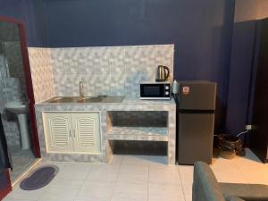 乔木提恩海滩Fullmoon Jomtien Guest house的厨房配有带水槽的柜台和冰箱。