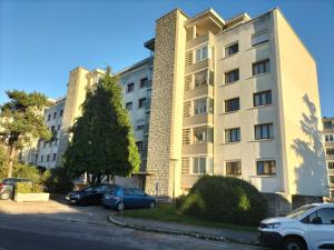 博瓦纪尧姆La Belle Epoque Rouen gare 5 min terrasse parking的停车场内停放汽车的大型建筑