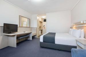 阿德莱德Comfort Inn Glenelg的酒店客房配有一张床和一张书桌及一台电视
