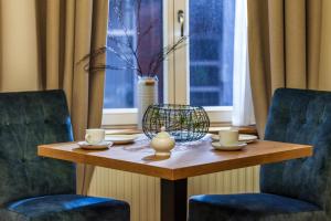 博尔库姆Commandeur-Huus Wohnung 2的一张带两把椅子的木桌和一张带杯子的桌子