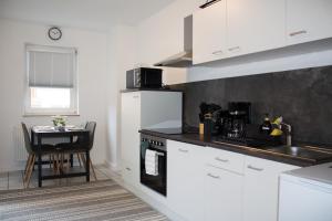不莱梅Timeless Apartment Bremen-Neustadt的厨房配有白色橱柜和一张带桌子的小桌子。