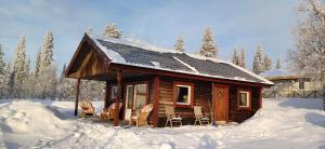 基律纳LAKESIDE AURORA CABINS的雪中带椅子的小木屋