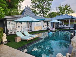 罗威那The Kayu Manis Villa的房屋旁的游泳池配有椅子和遮阳伞