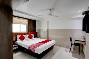 孟买Super OYO Flagship Hotel Everest Lodging Vashi的一间卧室配有一张带红色枕头的床和一张书桌