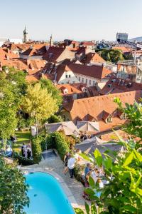 格拉茨Schlossberghotel的享有带游泳池和建筑的度假村的顶部景致