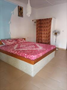 Diakène OuolofCAMPEMENT DIAMORAL DIAKENE OULOFF的一间卧室配有一张带粉红色棉被的床