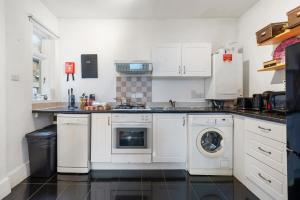 伦敦Modern Living in the Heart of Covent Garden! 6BC的厨房配有白色橱柜、洗衣机和烘干机