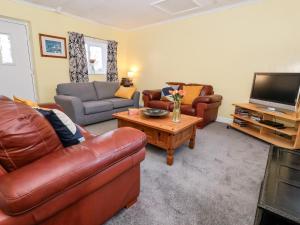 莫尔顿Millers Cottage的客厅配有皮革家具和平面电视