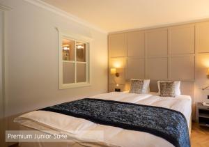 伦克Lenkerhof gourmet spa resort - Relais & Châteaux的一间卧室设有一张大床和一个窗户。