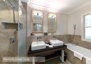 伦克Lenkerhof gourmet spa resort - Relais & Châteaux的浴室配有2个盥洗盆、淋浴和浴缸。