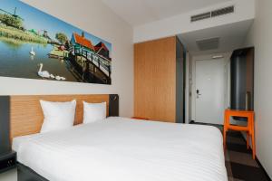 赞丹阿姆斯特丹赞丹轻松酒店的卧室配有白色的床和墙上的绘画作品