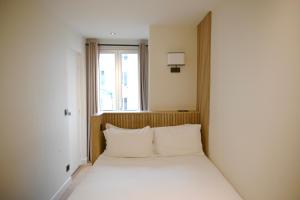 巴黎帕维侬蒙马特尔酒店的窗户客房内的一张带白色枕头的床