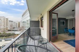 巴黎181 One Suite - Superb apartment in Paris.的大楼内的阳台配有两把椅子和一张桌子