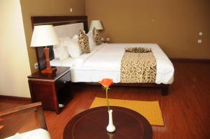 亚的斯亚贝巴Melka International Hotel的酒店客房,配有一张床和一张带花瓶的桌子
