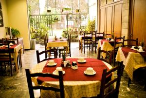 罗萨里奥Hotel Mayoral的餐厅设有桌椅,配有红色和白色的桌布