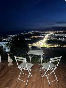 得土安Luxueux VILLA avec jardin et vue panoramique的晚上阳台上配有两把椅子和一张桌子
