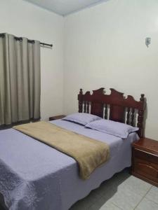 马卡帕casa de praia的一间卧室配有一张大床和木制床头板