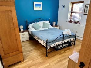 盖尔文Yr Encil的一间卧室配有一张蓝色墙壁和木地板。