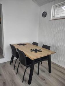 伊卢利萨特Ilulissat Hostel的一张带椅子的木桌和墙上的时钟