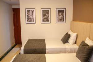 波哥大Hotel ByHours Las Américas的酒店客房,设有两张床,墙上有三幅画