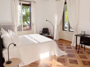 蒙特勒Montreux Luxury Suite的白色卧室设有床、书桌和窗户