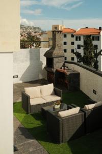 丰沙尔CASA15 Guesthouse Funchal的一个带两张沙发的庭院和一个带壁炉的阳台