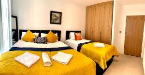 伦敦Dockland Excel 2 Bedroom Apartment的一间卧室配有两张带黄床单的床