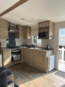 纽基Beautiful Caravan With Decking At Trevella Holiday Park, Newquay, Ref 98082hs的厨房配有木制橱柜和炉灶烤箱。
