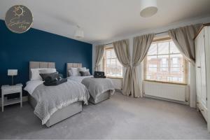 利明顿Leeward House - Luxury, Spacious, Sea View Apartment, Parking, Central Lymington的卧室设有两张床铺,拥有蓝色的墙壁和窗户