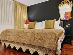 利马ANA FRANK Boutique Hotel的一间卧室配有一张大床和金框镜子