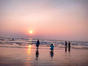 戴维格Om Laxmi Narayan Homestay的一群人日落时在海滩上散步