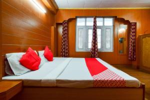 西姆拉OYO Flagship Hotel Unique的一间卧室配有一张带红色枕头的床和一扇窗户