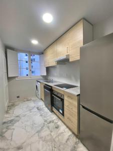 瓦伦西亚Central Rooms & Suites at Bruno Valencia Apartments Downtown的厨房配有木制橱柜和冰箱。