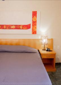 伊利亚贝拉Beira mar Flat 2-209的一间卧室配有一张床和一张带台灯的桌子