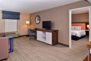 恩波里亚恩波里亚汉普顿酒店的酒店客房配有一张床和一张书桌及一台电视